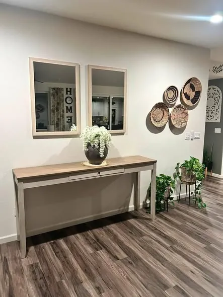 Cleaned entryway with a console table, twin mirrors and woven wall baskets